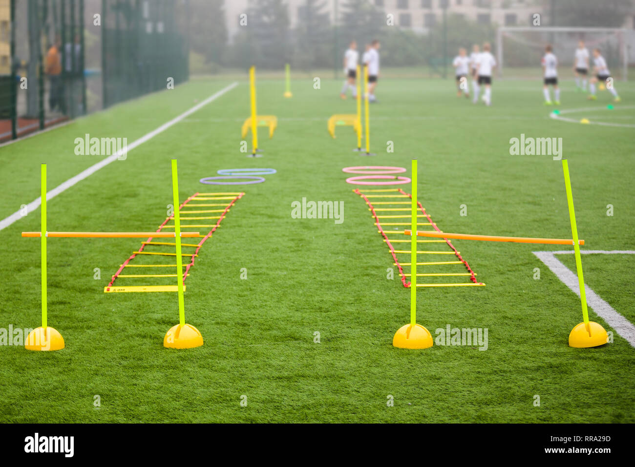 Soccer field with training equipment and fence in background. Junior football team training with coach in the background. Soccer football training Stock Photo