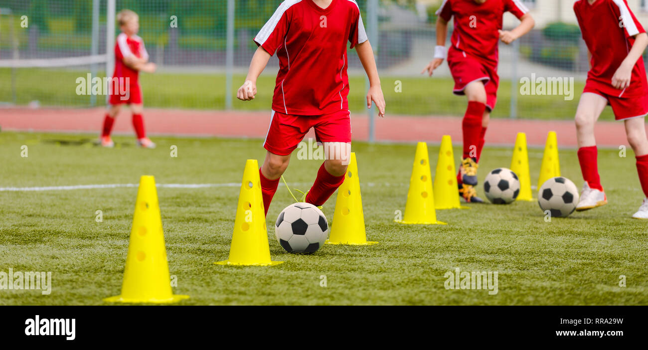 Soccer camp for kids. Boys practice dribbling in a field. Players develop good soccer dribbling skills. Children training with balls and cones. Soccer Stock Photo