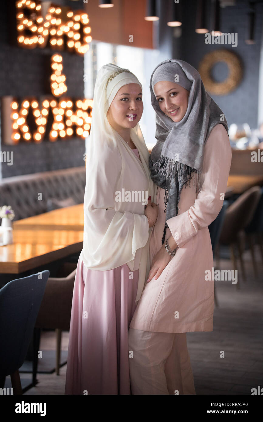 Two young muslim smiling women standing in the cafe Stock Photo