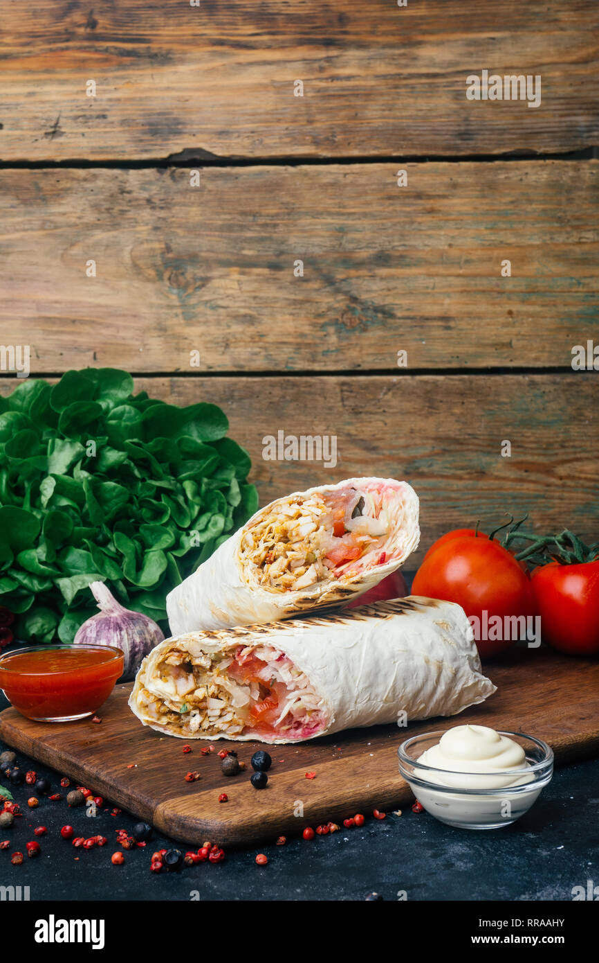 Doner kebab (shawarma or doner wrap). Grilled chicken on lavash (pita  bread) with fresh vegetables - tomatoes, green salad, peppers. Old wooden  backgr Stock Photo - Alamy