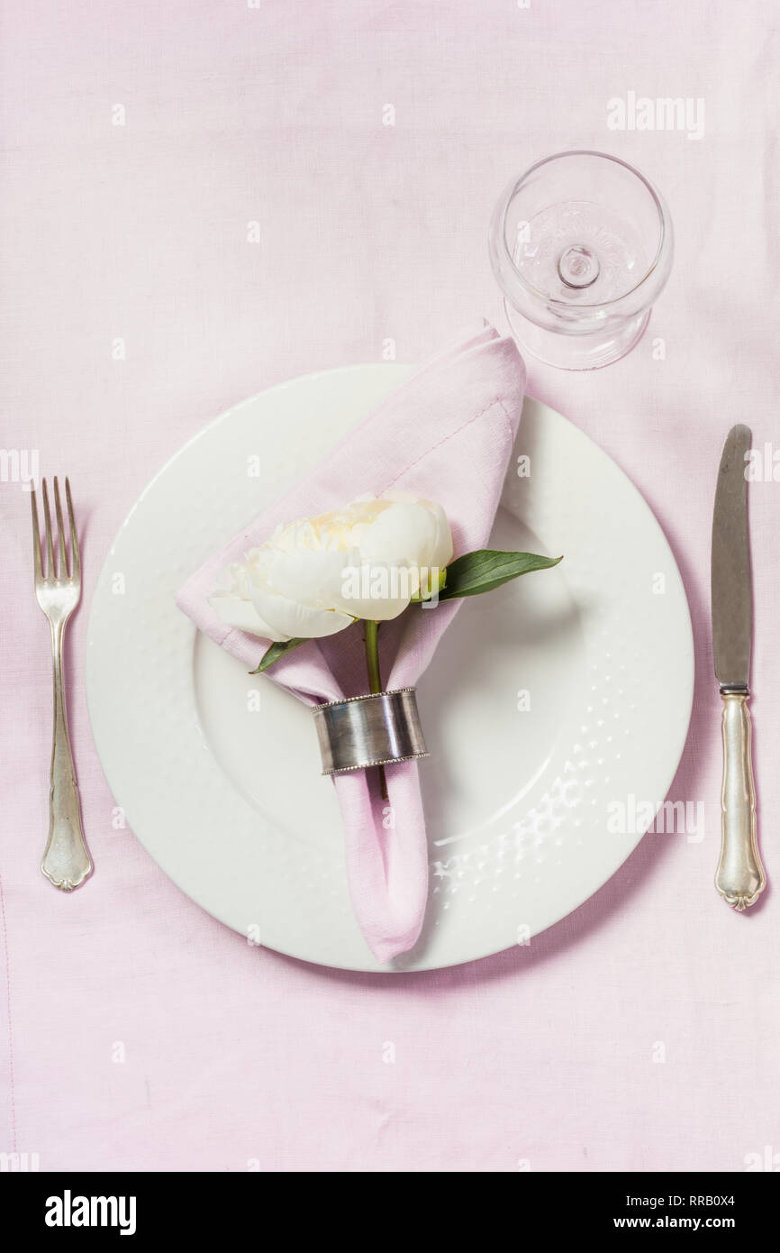 Spring romantic dinner. Elegance table setting peony flowers on tablecloth. Top view. Stock Photo