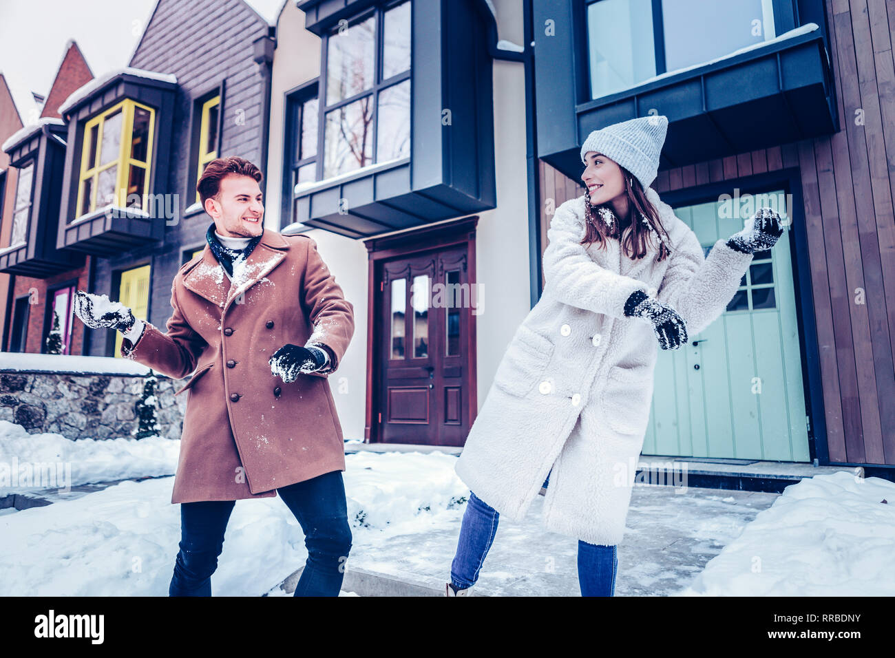 Happy couple feeling amazing playing snowballs near their house Stock ...