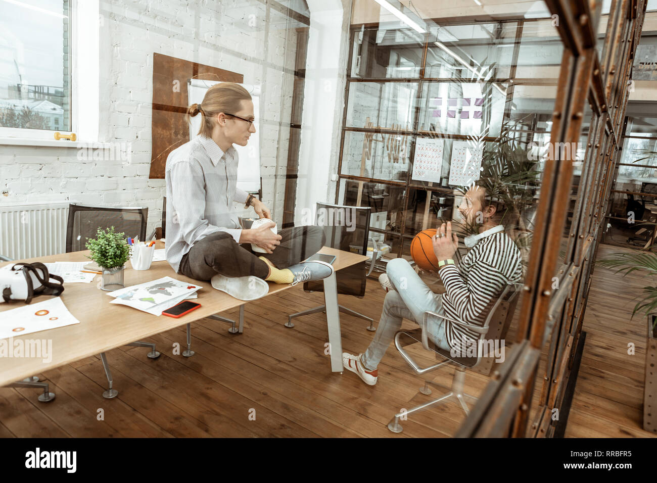Pleasant young man sitting on the table Stock Photo