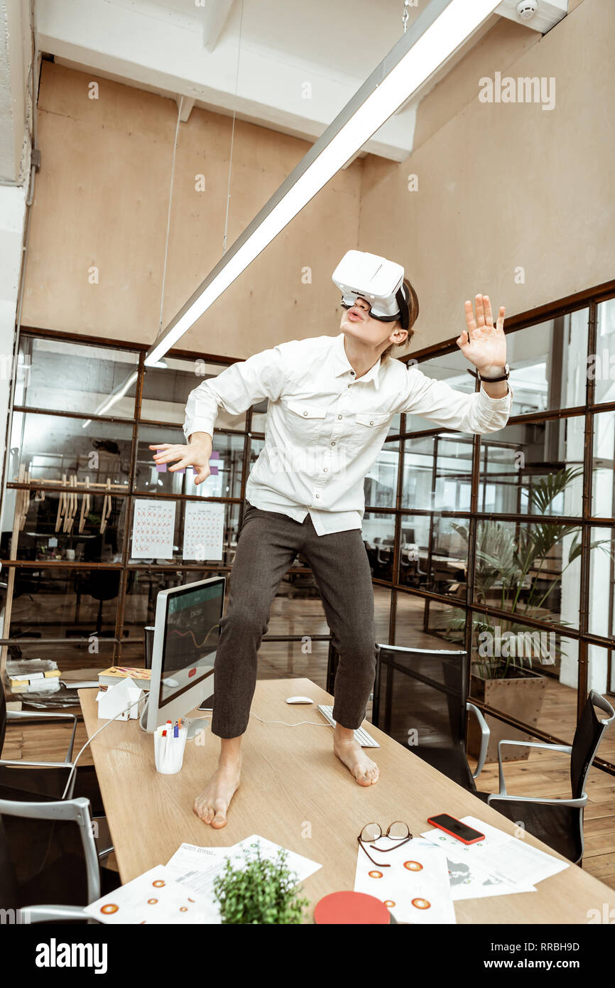 Pleasant young man standing on the table Stock Photo