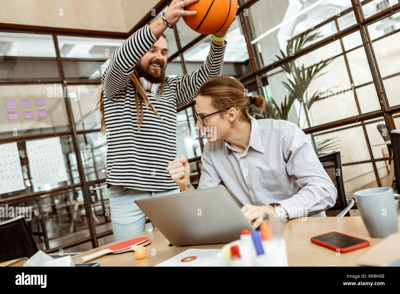 Delighted happy man distracting his colleague from work Stock Photo