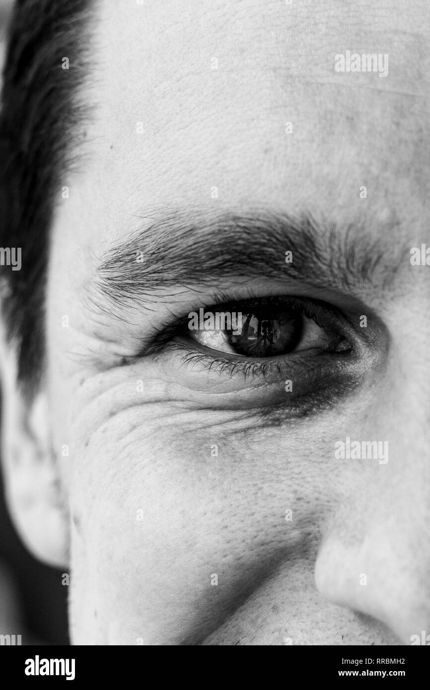 Fragment of a man's face: right eye and nose to compile an identikit. Fragment of the wrinkled face of a young guy. Smiling eye of a man. Black and wh Stock Photo