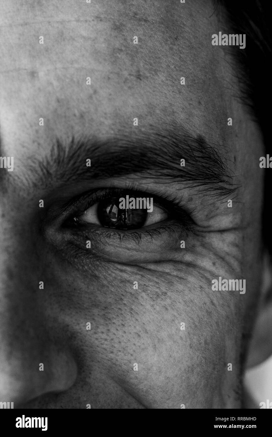 Fragment of a man's face: left eye and nose to compile an identikit. Fragment of the wrinkled face of a young guy. Smiling eye of a man. Black and whi Stock Photo