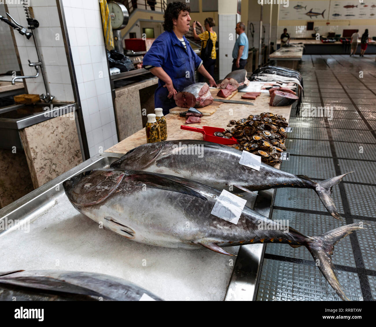 Fishmonger selling tuna at the Lavradores fish market, Funchal, Madeira, Portugal. Stock Photo