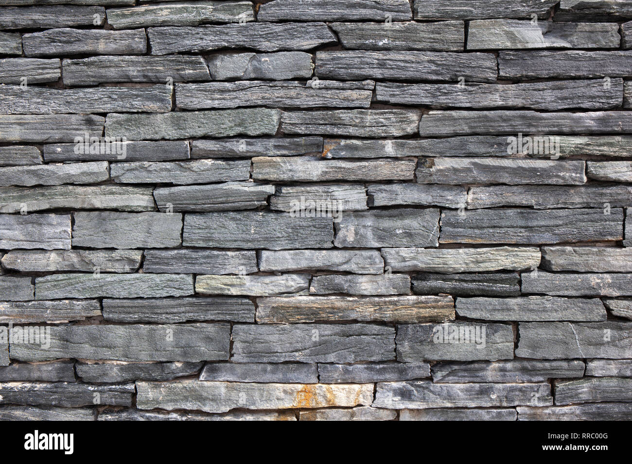 Grey stone granite wall made of stacked pieces stones. Full frame image ...