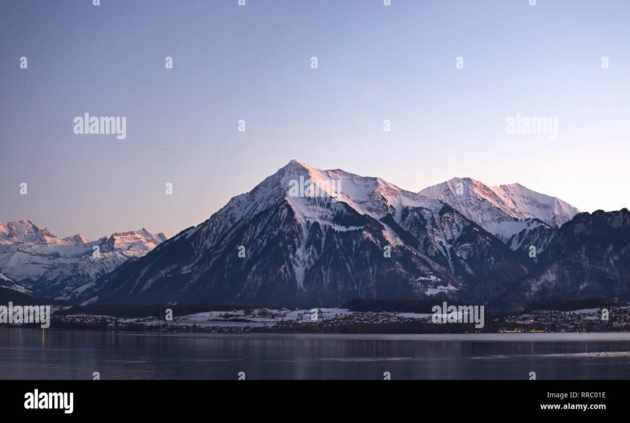 Lake Thun and the mountain Niesen during twilight with reflection of little village lights in the lake. Stock Photo