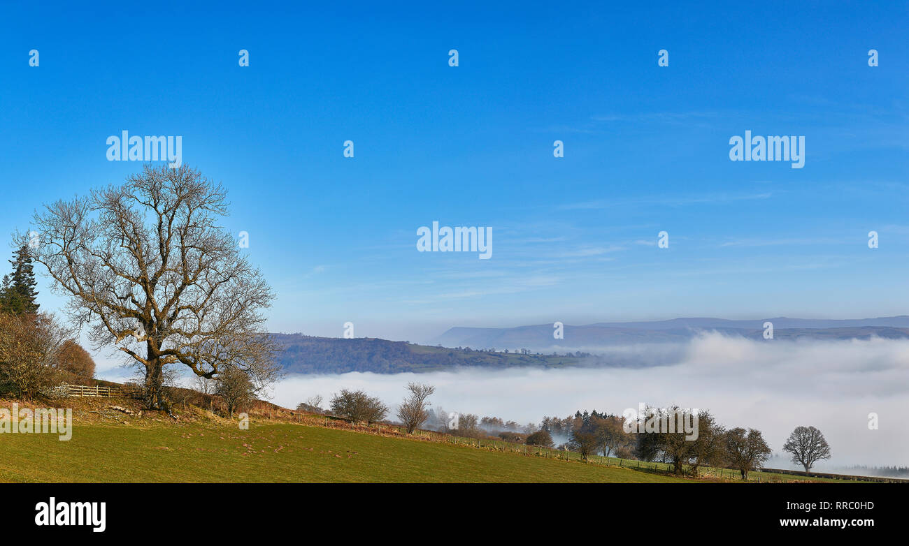 A dramatic cloud inversion taking place in The Brecon Beacons National Park on a bright cloudless morning in February, Wales, UK Stock Photo