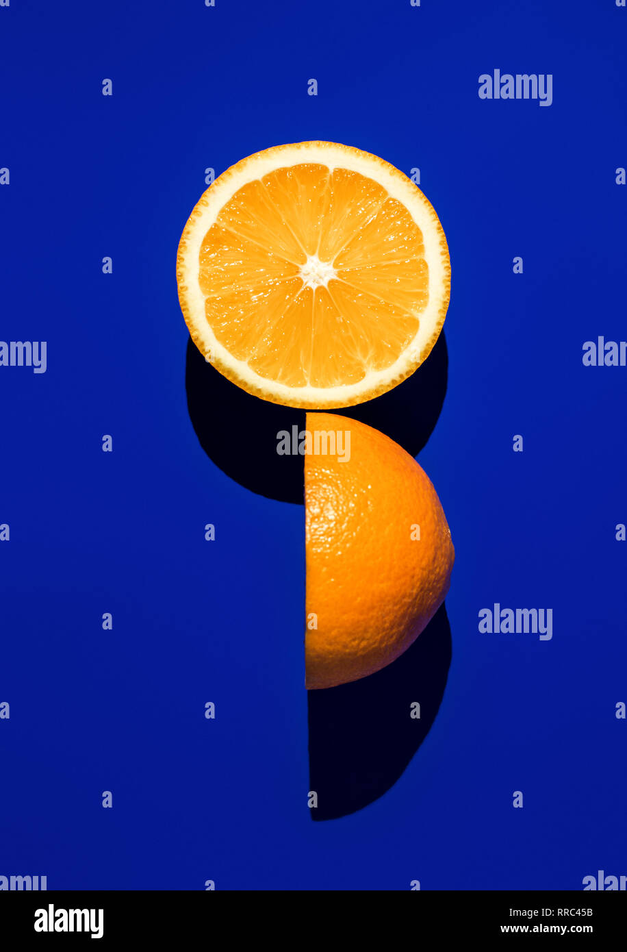 Two halves of ripe orange on a blue background in bright sunlight Stock Photo