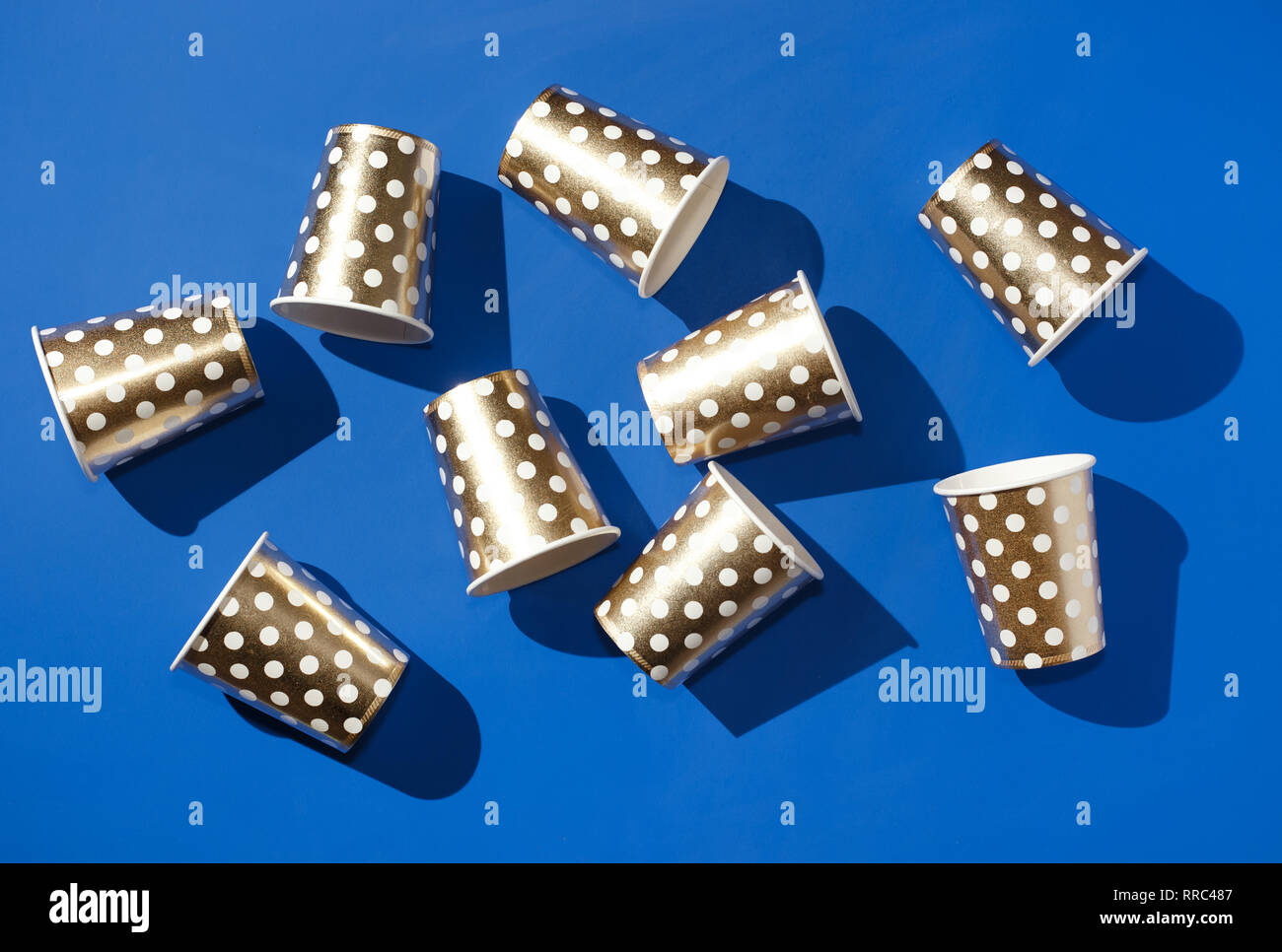 Golden paper cups for birthday party on blue background Stock Photo