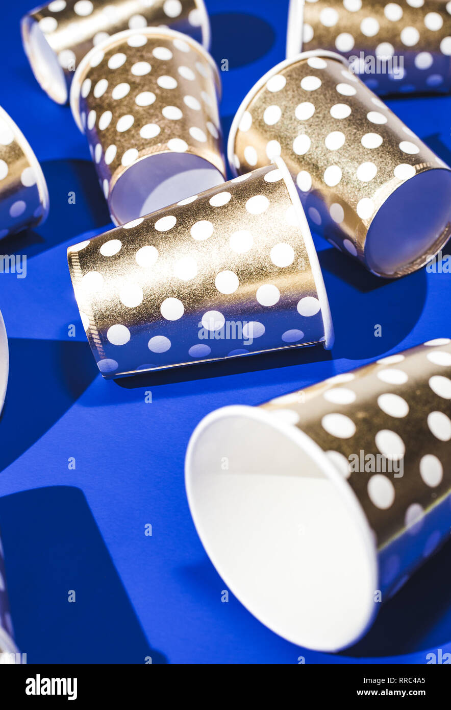 Golden paper cups for birthday party on blue background Stock Photo