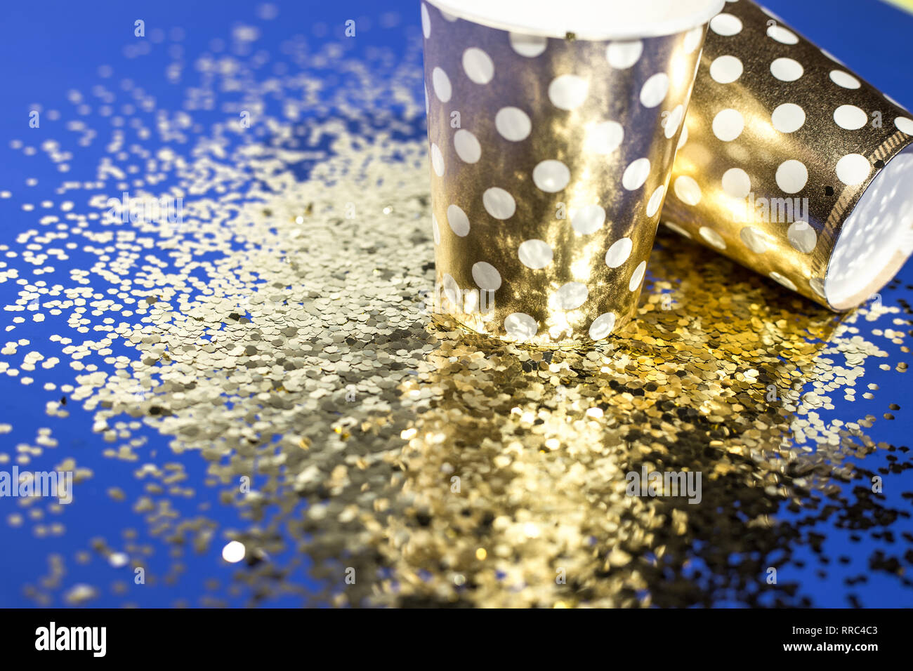Golden paper cups for birthday party with golden confetti on blue ...