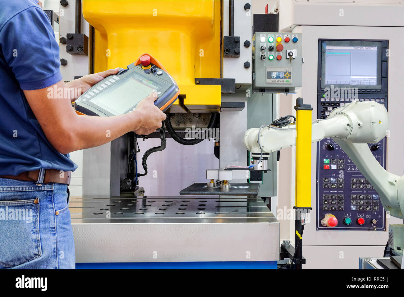 Engineer use wireless remote for control industrial robot working on ...