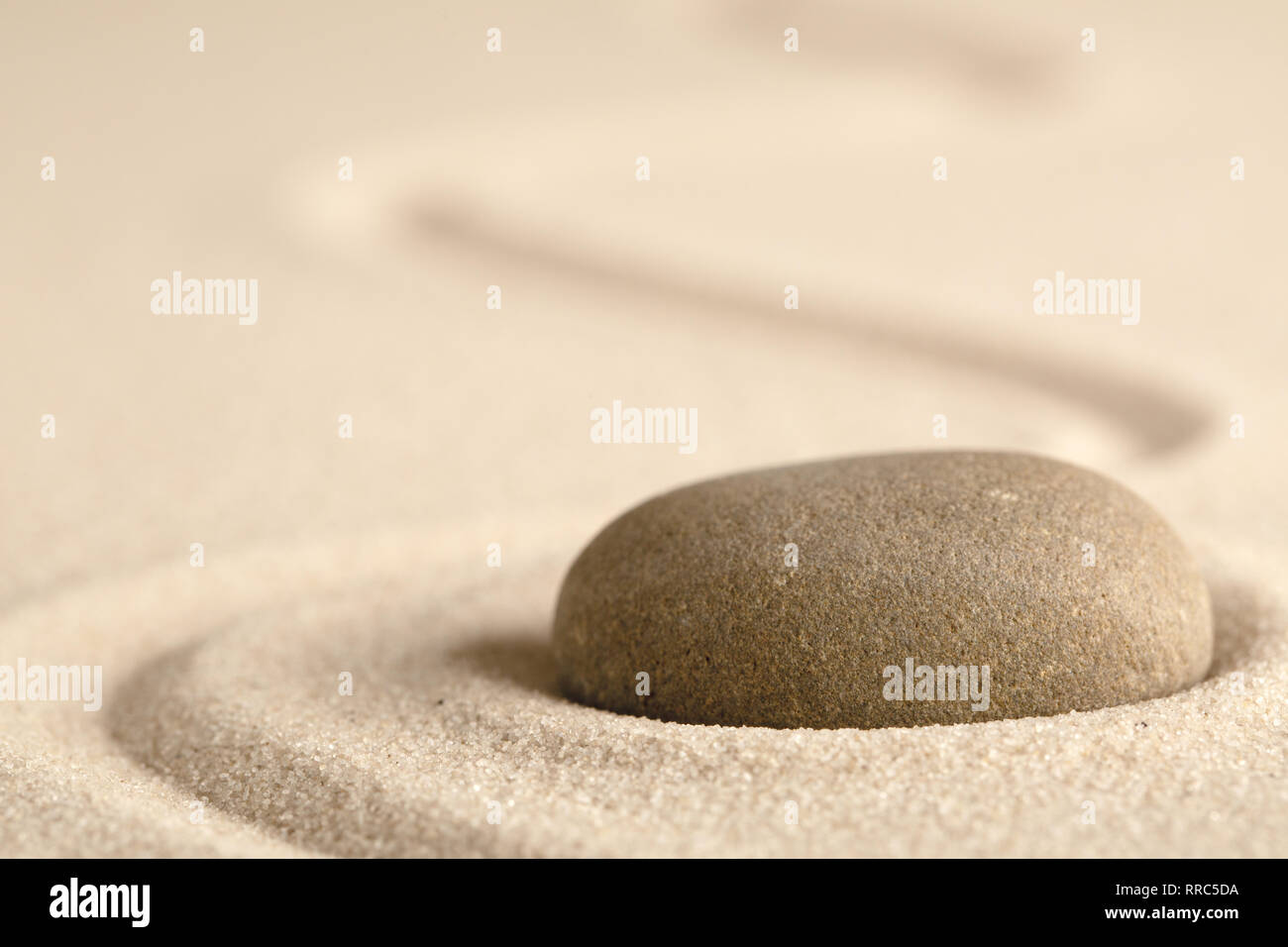 Zen meditation stone with raked line in sand. Concept for harmony relaxation and purity. Stock Photo