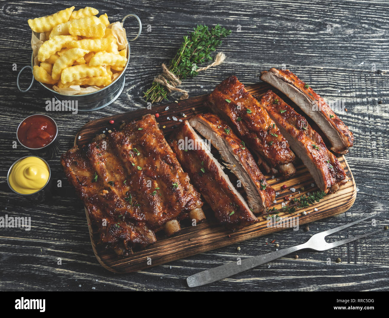 grilled pork ribs with sauce on a cutting board, french fries Stock Photo