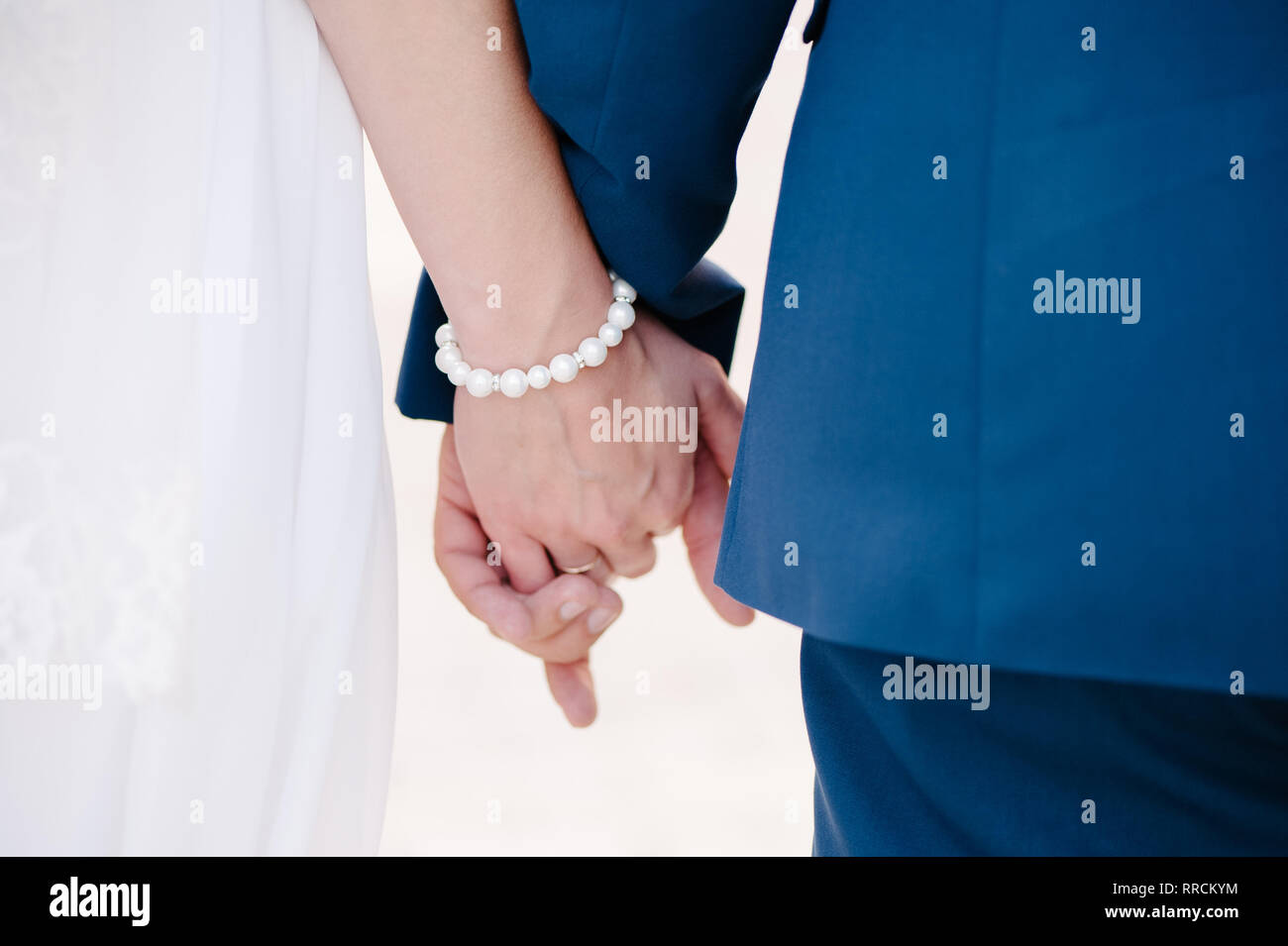 Newlyweds staying together and holding arm in arm Stock Photo