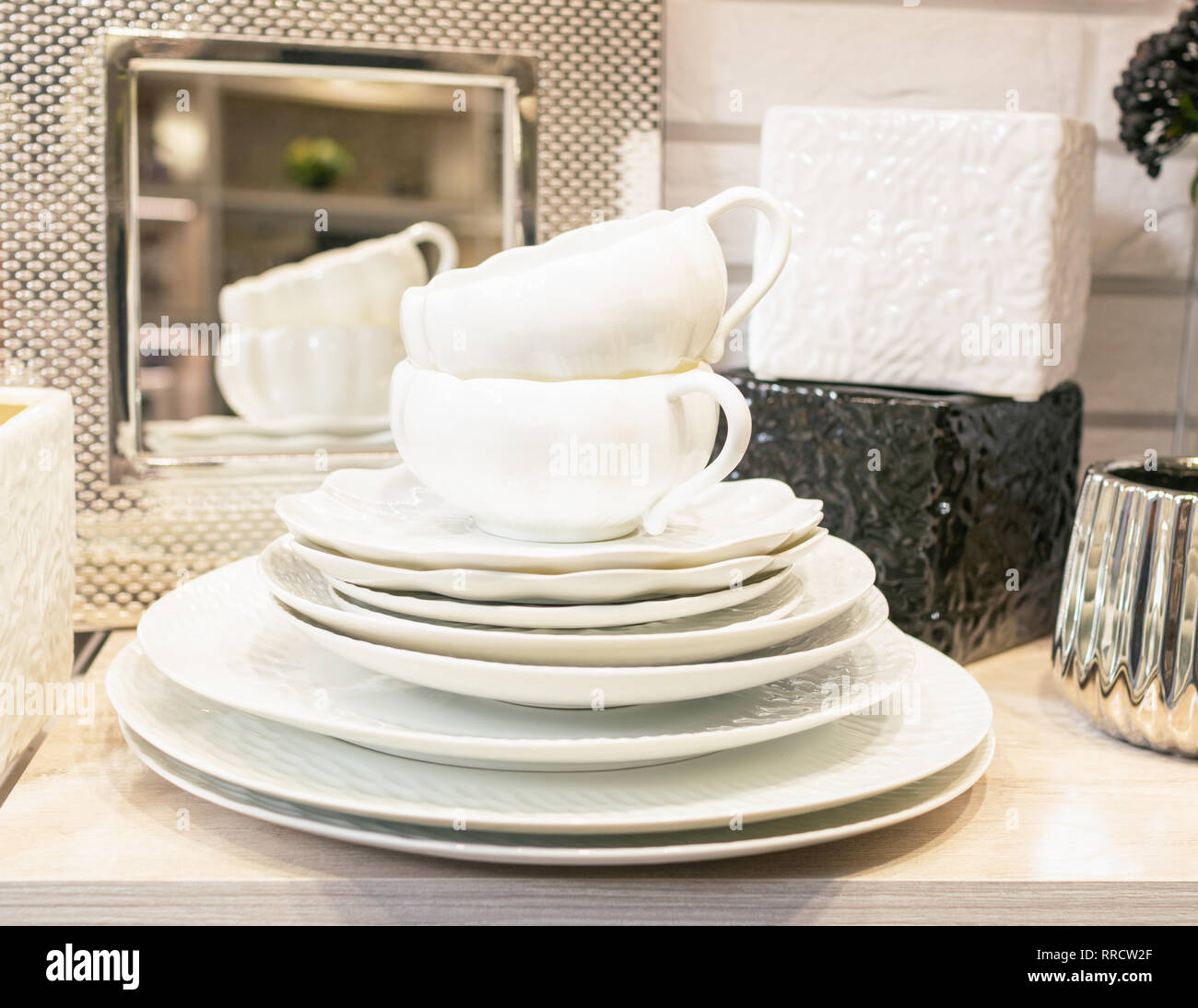 A stack of clean empty white porcelain tableware on a shelf