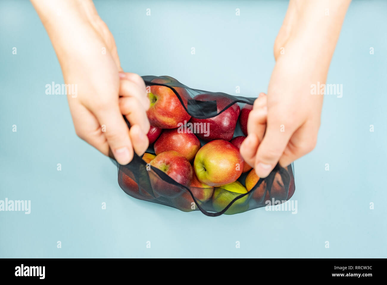 Holding a reusable string bag full of apples. Sustainable eco packaging concept: shopping for groceries with a multi-use bag to reduce ecological foot Stock Photo