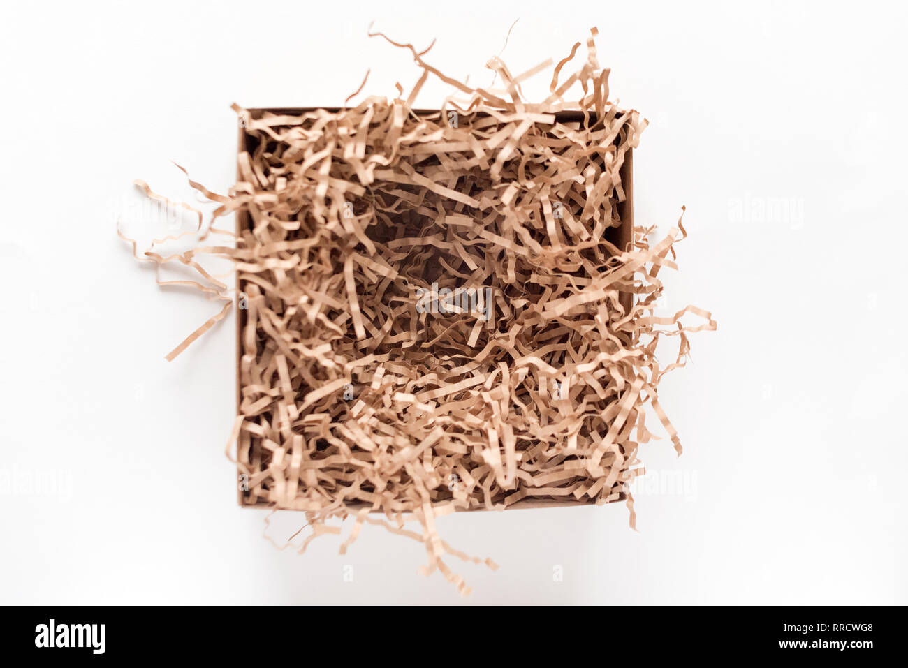 Opened gift box with decorative straws fillers on light background