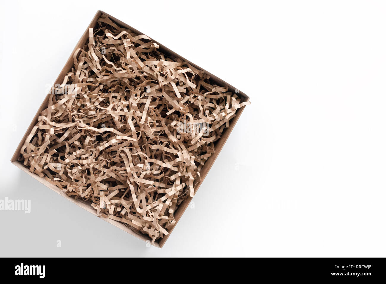 Opened gift box with decorative straws fillers on light background