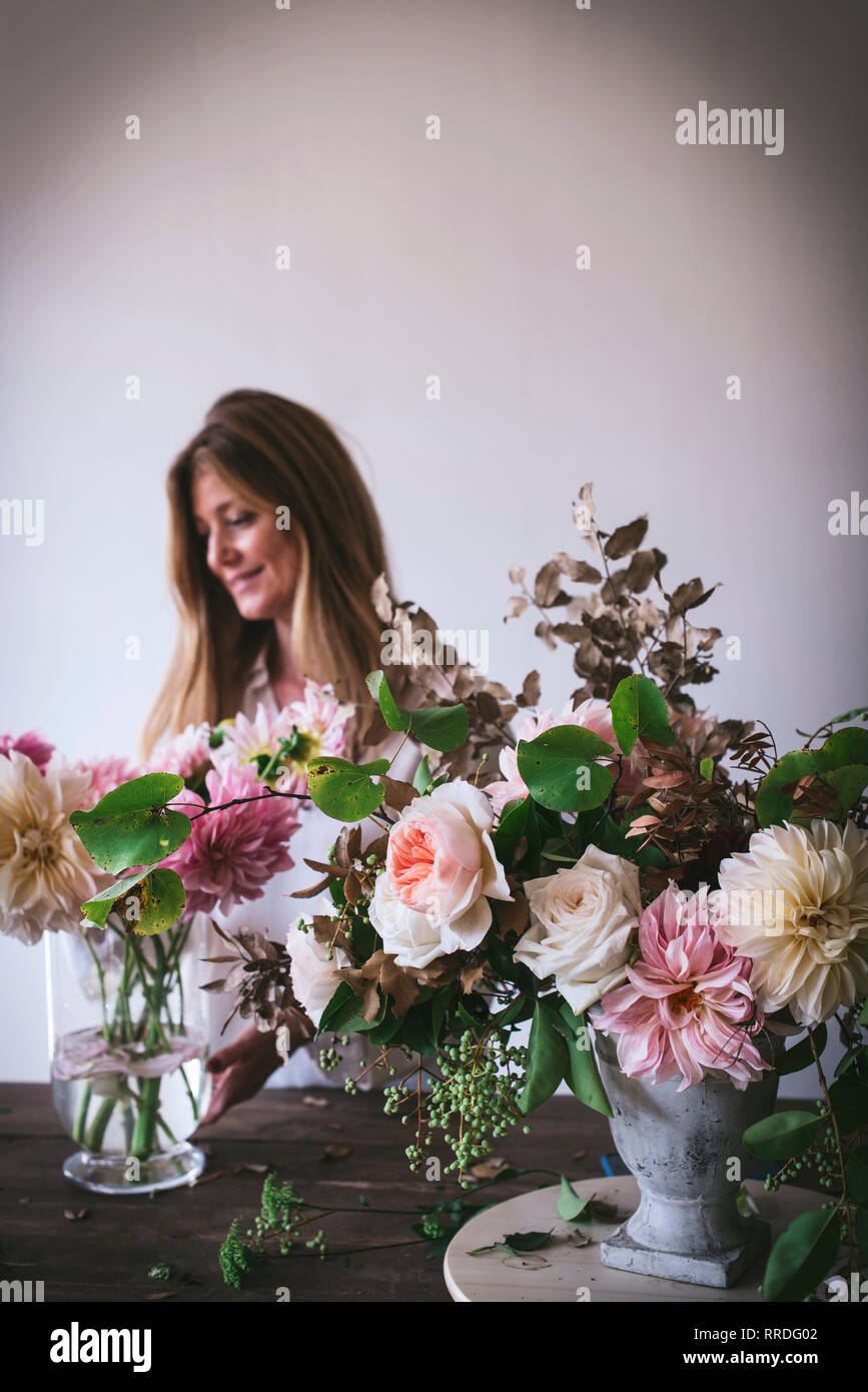 Happy Lady Near Wooden Table With Bunches Of Fresh Chrysanthemums
