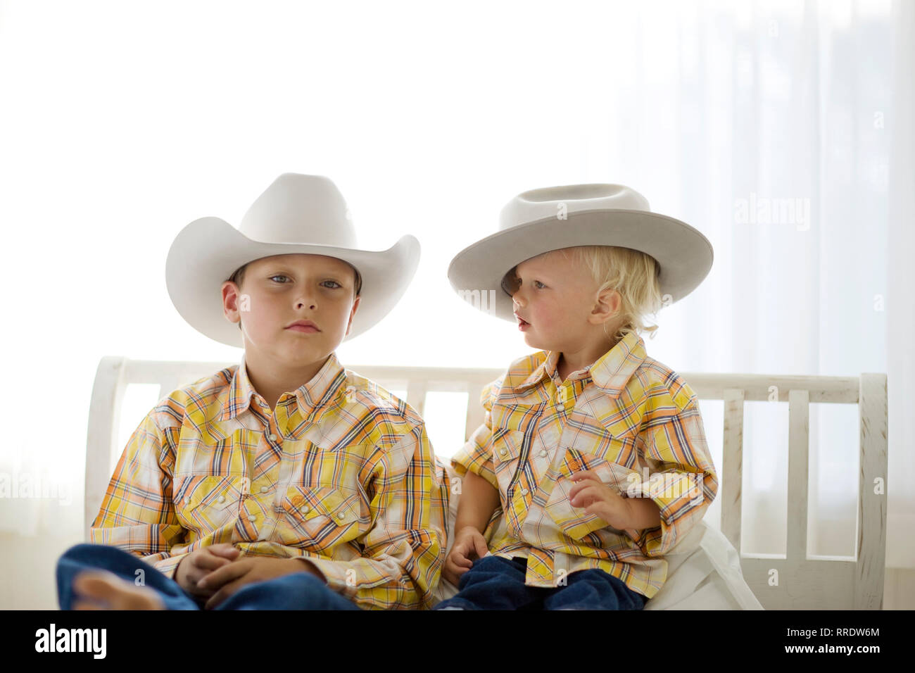 Portrait of a boy wearing a cowboy hat while sitting next to his younger brother. Stock Photo