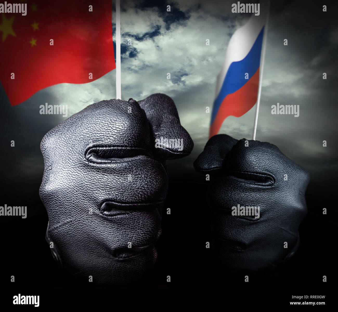 Two gloved hands arriving with flags, one Chinese the other Russian. In the background, the sky covers a black horizon. Stock Photo