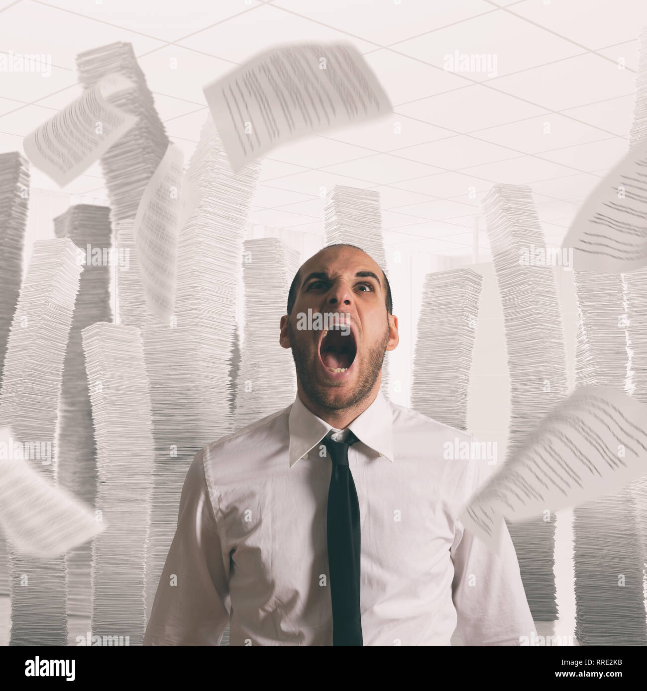 Businessman stressed and overworked screaming in office with flying paper sheets Stock Photo