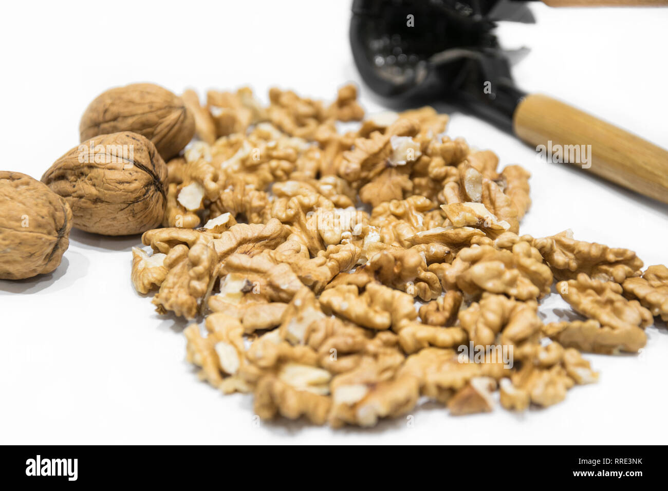 Nutcracker, walnut kernels and whole nutshells closeup macro, isolated on a white background. Dried fruit Stock Photo