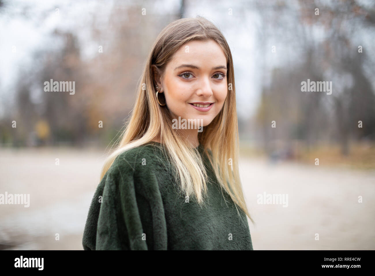 Portrait of happy smiling young blond woman in a park in autumn Stock Photo