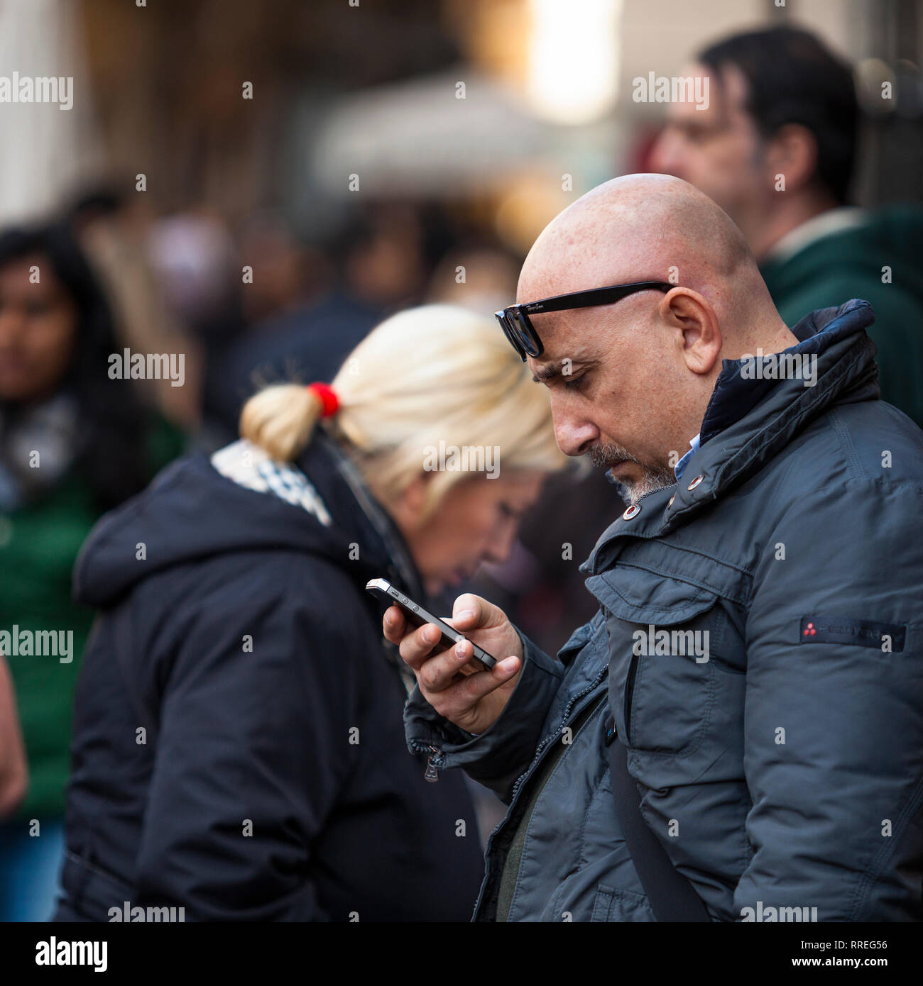 Man in a Crowd looking at Mobile Phone Stock Photo
