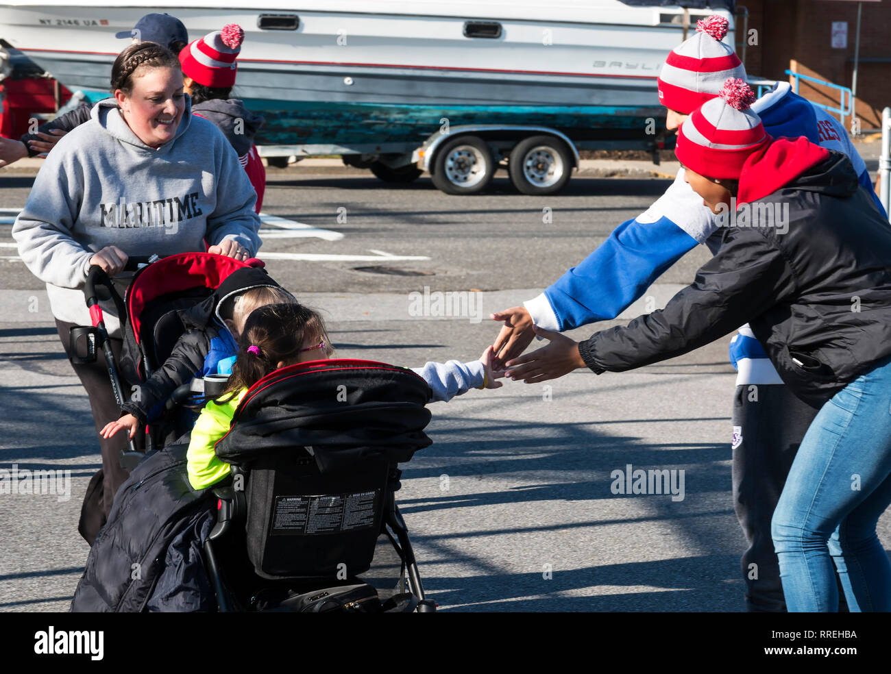 West Islip, NY, USA - 24 November 2017: Even the kids in a stroller get high fives as they get closer to the finish line of the annual Run Your Turkey Stock Photo