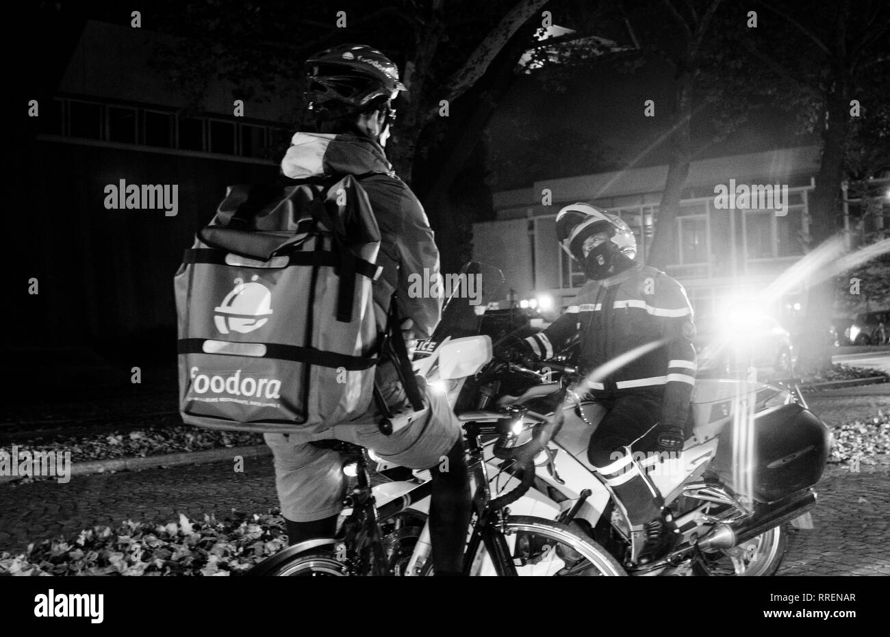 Strasbourg, France - Oct 27, 2018: Police officer blocking the street - Foodora cyclist delivering food waiting due to official delegation visit - black and white Stock Photo
