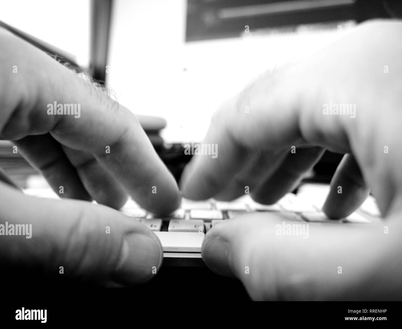 Male hands fast typing working on computer keyboard writing playing using modern computer with white caps and cyrillic and english characters - black and white Stock Photo