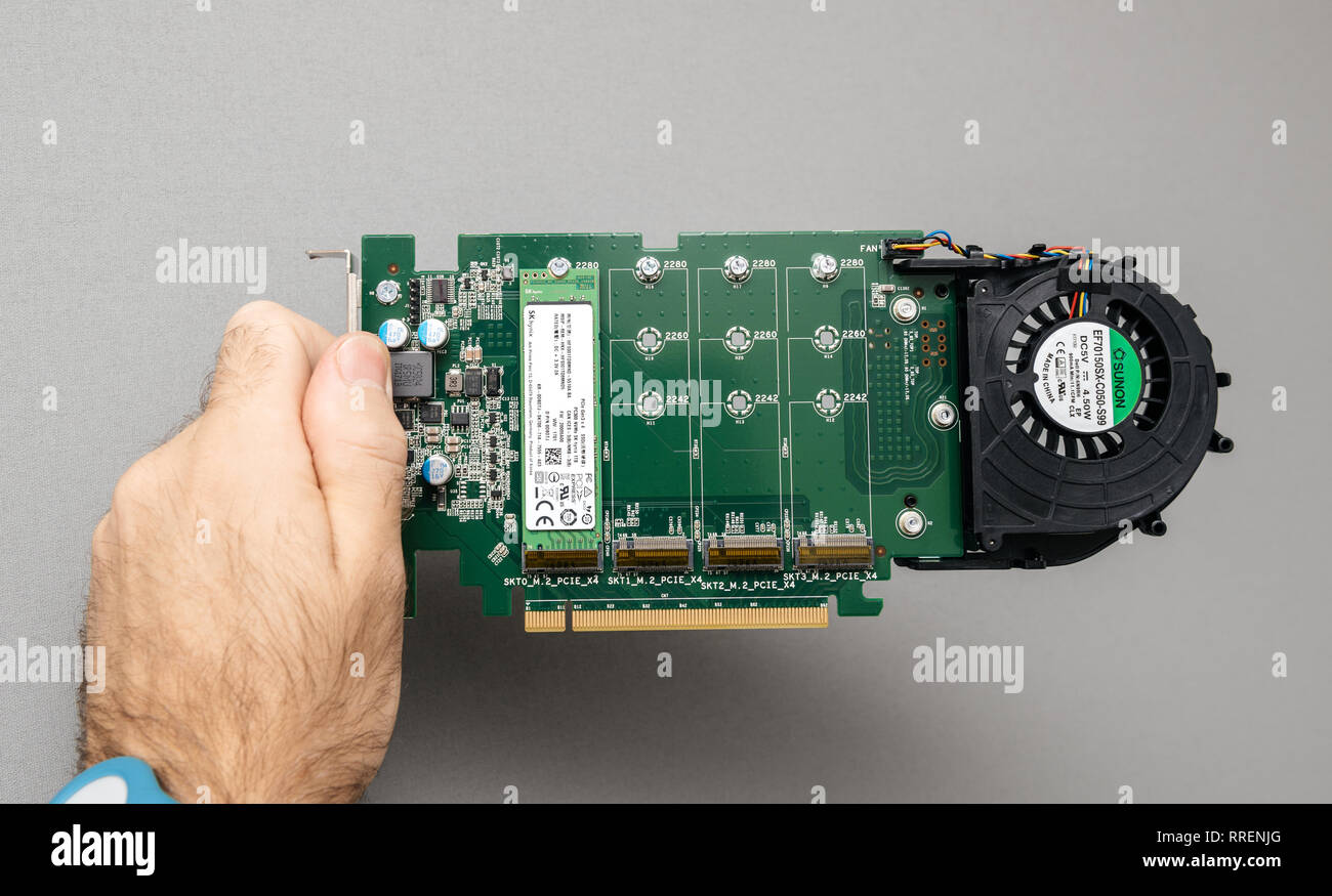 Paris, France - Oct 14, 201 : Man IT guy holding against gray background a powerful open Dell Ultra-Speed Drive Quad NVMe M.2 PCIe x16 Card with one SK Hynix card with Sunon fan Stock Photo