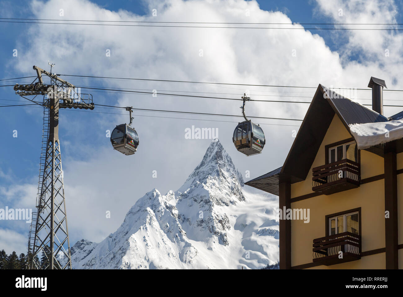 DOMBAY, RUSSIA, FEBRUARY 28, 2018: Cabins of the ski lift against the high snow-capped Caucasus Mountains Stock Photo