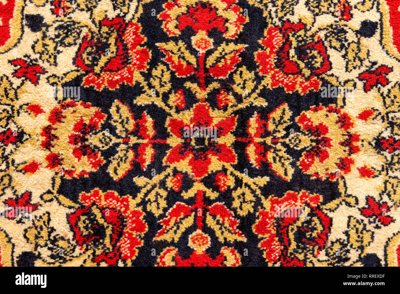 Ornament details of a vintage Persian carpet of vivid red, brown, yellow and black colors. Textile pattern or background Stock Photo