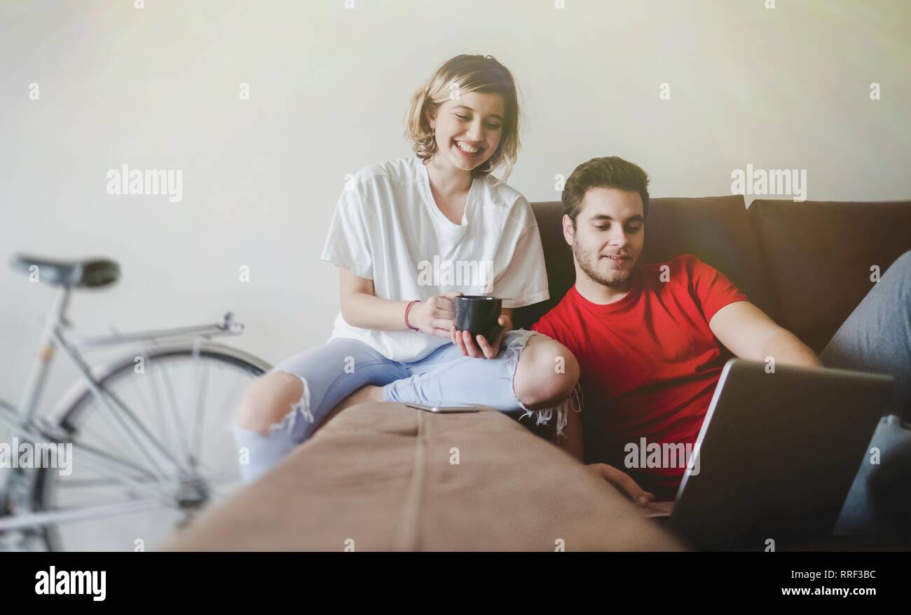 Cheerful couple laying down on the couch with computer Stock Photo