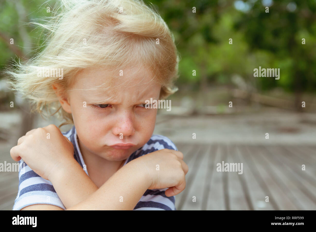 Face portrait of annoyed and unhappy caucasian kid with crossed arms. Upset and angry child concept for family relations, social problems issues Stock Photo