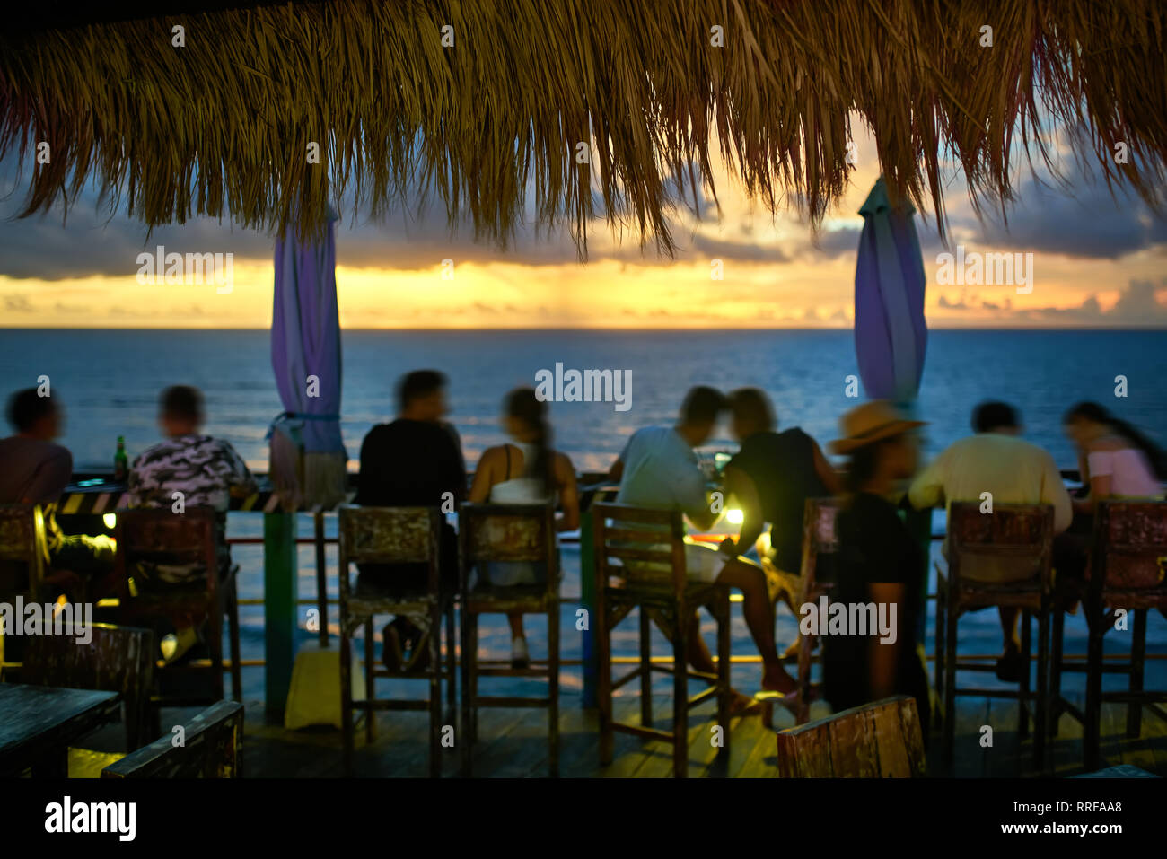 People are relaxing by the wooden rack on the terrace of the outdoor cafe  on the breathtaking background of the sunset sky and the sea on Bali.  Horizo Stock Photo - Alamy