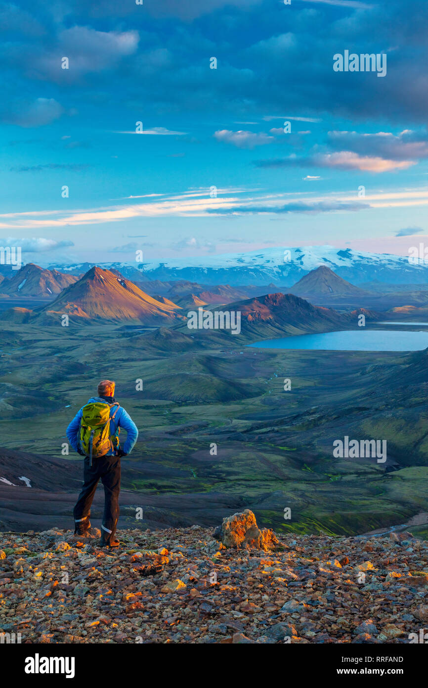 Evening hiker looking over the mountains and lake at Alftavatn, from Jokultungur on the Laugavegur hiking trail. Central Highlands, Sudhurland, Icelan Stock Photo