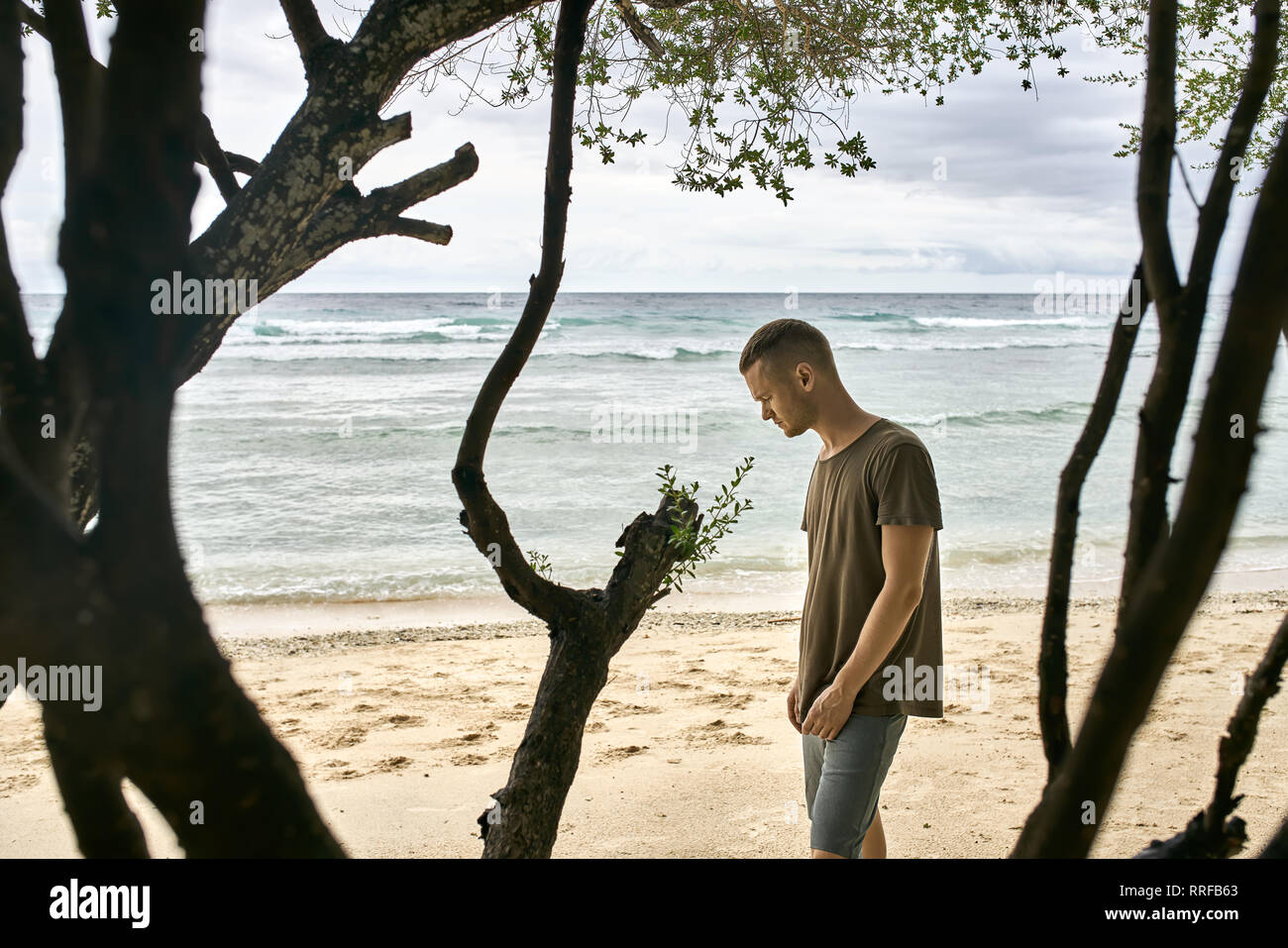 gray shorts stands near a green tree 