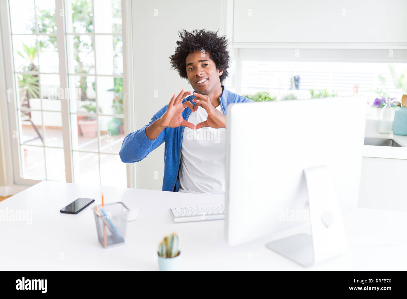 African American man working using computer smiling in love showing ...