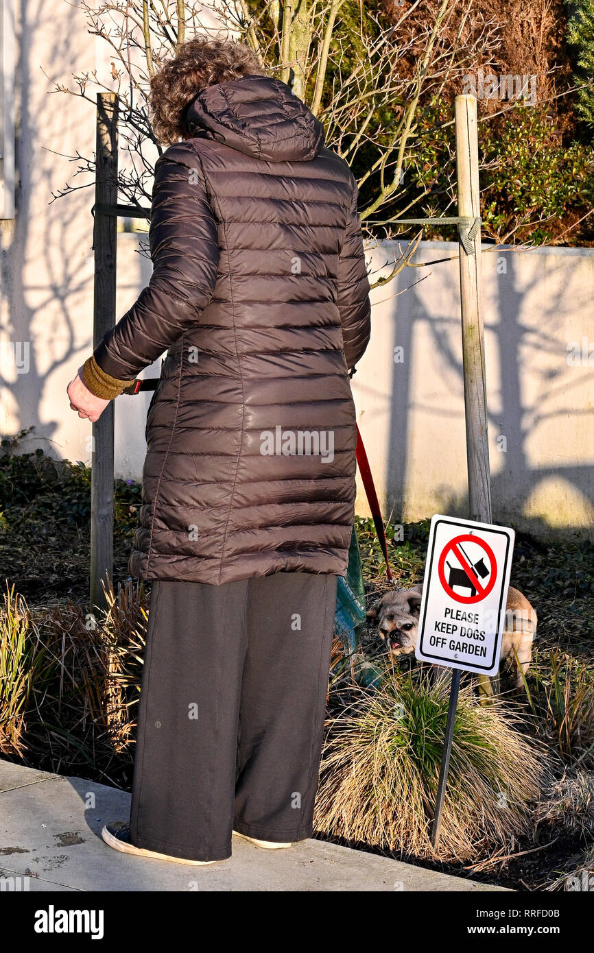 woman defying keep dogs off garden sign Stock Photo