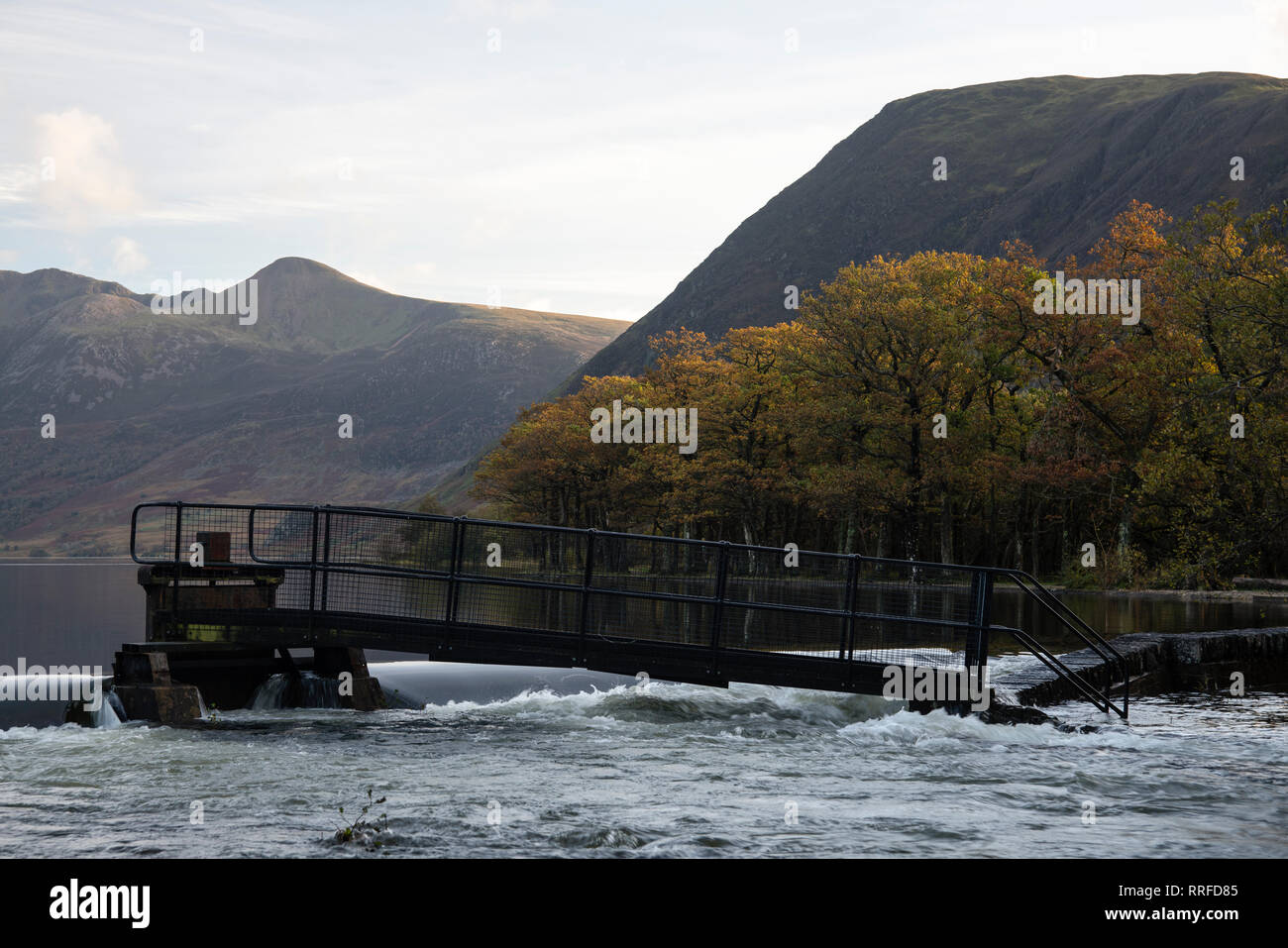 Fast flowing water over a weir at Crummock Water, Lake District, Cumbria, England, UK Stock Photo