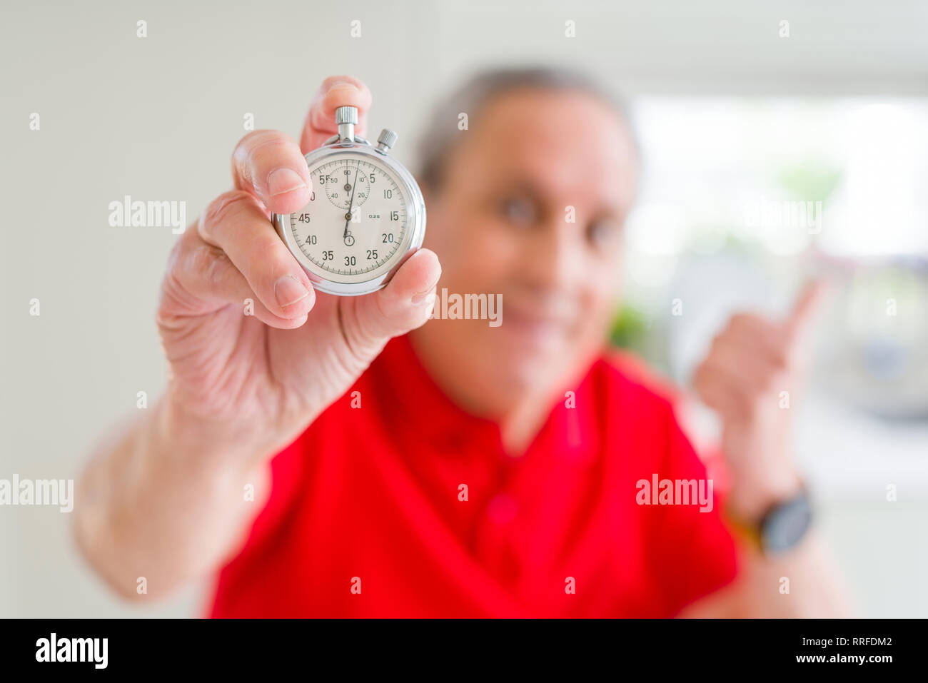 Handsome Senior Man Holding Stopwach Showing Countdown Pointing And Showing With Thumb Up To The 