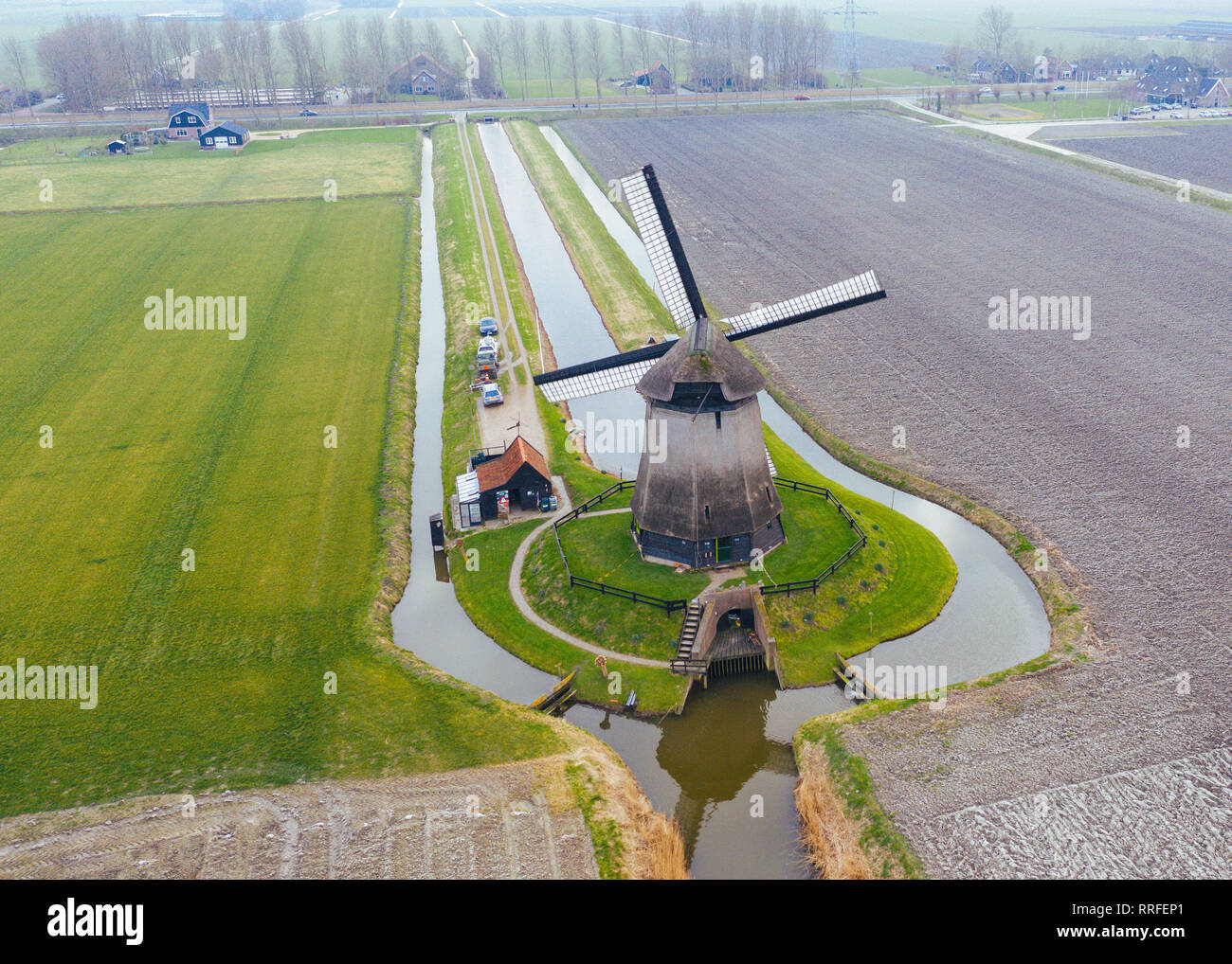 Typical Dutch windmill from the 17th century shot from above with a drone surrounded by a canal in the fields of holland Stock Photo